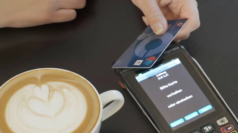 Person führt eine kontaktlose girocard-Zahlung an einem Kartenlesegerät in einem Café durch